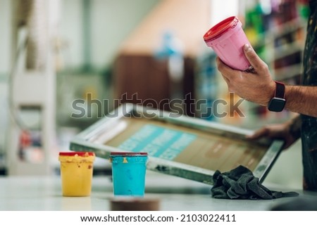 Male worker mixing colors for screen printing in a workshop
