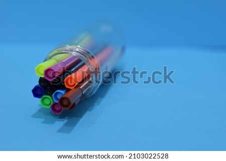 Selective Focus of A Set of Colourful Magic Ink Pens in A Plastic Container Isolated with Blue Background