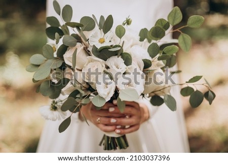 Very beautiful wedding bridal bouquet, made of white roch and austoma, and yellow daisies, green casting of eucalyptus.  Wedding, engagement. Bride and groom. Bride's wedding bouquet. Royalty-Free Stock Photo #2103037396