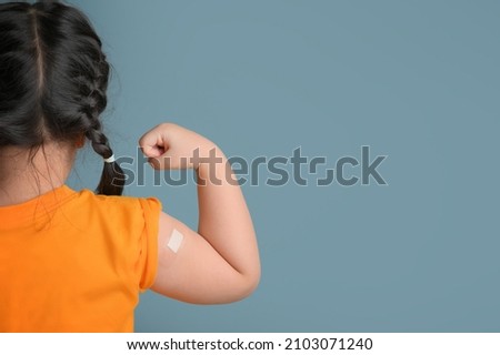Little asian child girl with bandage plaster on her arm after Covid-19 vaccination. Injection covid vaccine, healthcare for children Royalty-Free Stock Photo #2103071240