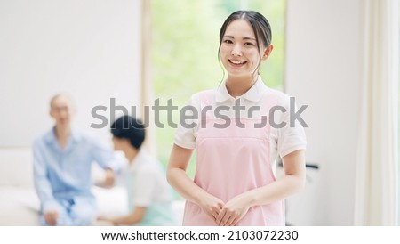 Smiling Asian caregiver. Elderly care facility. Royalty-Free Stock Photo #2103072230