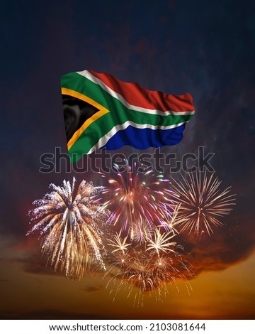 Holiday fireworks in evening sky and flag of South Africa for National Independence day
