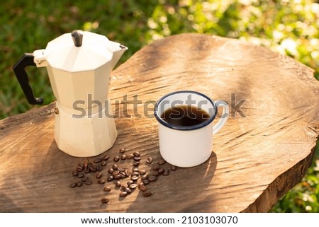 Selective focus white enamel coffee mug and morning coffee set in the garden.soft focus.shallow focus effect.