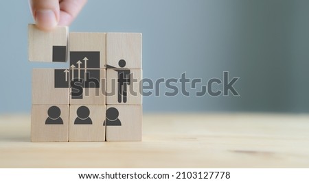Training and knowledge sharing concept. Workforce and team training plan and management. Businessman flips the wooden cubes with training symbols on beautiful white background and copy space. Banner. Royalty-Free Stock Photo #2103127778