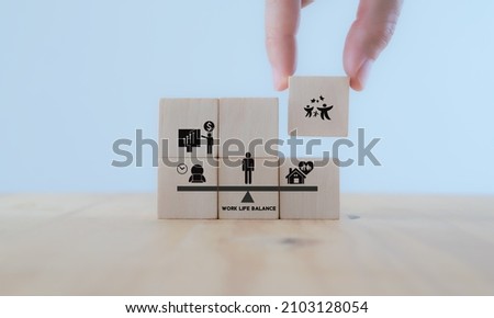 Work life balance concept. Work and home scales. Comparison work, finance and family. Hand holds the wooden cubes with family icon standing with work, money icon on white background and copy space.