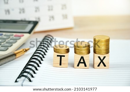 Tax concept with wooden blocks on stacked gold coins on business background.                            
