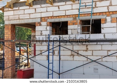 Building site of a house under construction. Unfinished house walls made from white aerated autoclaved concrete blocks. Wooden truss system