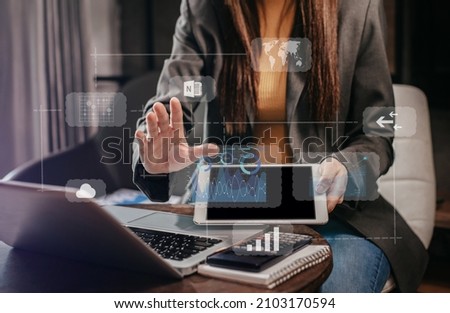 Businesswomen or Designer using tablet with laptop and document on desk in modern office with virtual interface graphic icons network diagram.