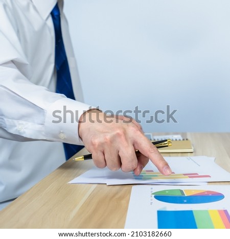 vertical of executive ​point data graph on document on working desk by hand with white copy space for making meeting presentation, professional businessman busy work on the business data graph