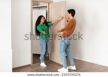 Welcome. Portrait of excited lady greeting guy meeting him at front door, wants to hug, inviting guest to enter her flat, welcoming home, happy couple standing in doorway of new modern apartment
