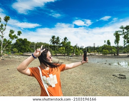 Asian selfie girl thumbs up at the beach on her holiday in southern Thailand.
