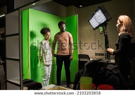Female studio staff standing in front of green screen background and preparing to shooting
