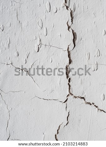 many cracks on the light wall. Textured background. Vertical orientetion