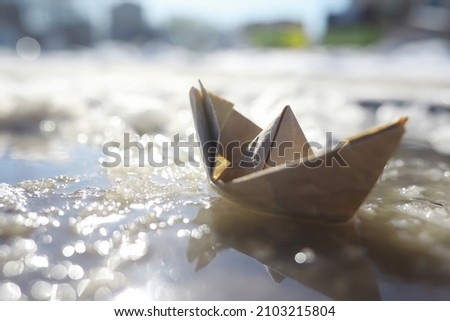 Paper boat in the water on the street. The concept early spring. Melting snow and an origami boat on water waves.