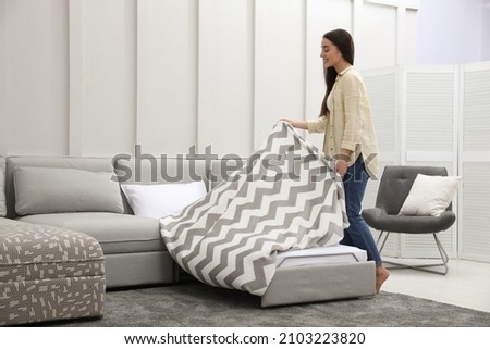 Woman making sleeping place for guest in living room. Convertible sofa Royalty-Free Stock Photo #2103223820