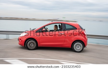 Young girl enjoying driving her little red car Royalty-Free Stock Photo #2103235403
