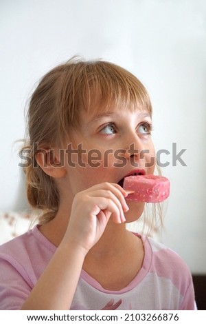 Ten years old blond hair girl with pink ice cream in her mouth