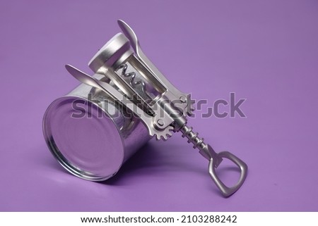 Close up various metal and white tin can on purple background. Metal can opener.