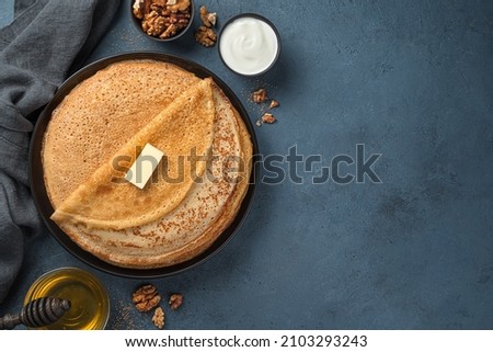 Traditional fried pancakes on a dark background with honey, nuts and sour cream. Maslenitsa, Russian blini. Top view., copy space.