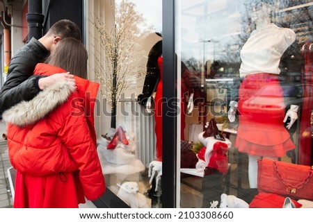 New Year's sale. A guy and a girl looking in the window of a fashion boutique, outside