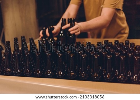 Glass products. Bottles for drinks. Industrial work, automated production of food and drinks. Details of local beer production line, Many bottles on conveyor belt in factory