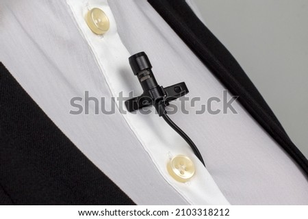 small audio microphone for voice recording with a clothespin attached to a woman's shirt.