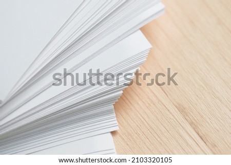 Stack of clean sheets paper, laid out randomly in wooden background. Abstract background of paper sheets Royalty-Free Stock Photo #2103320105
