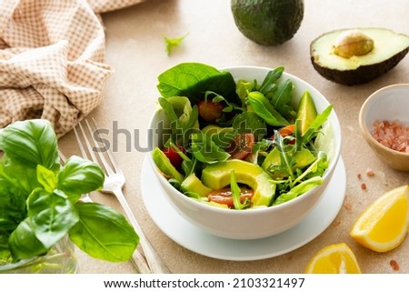 Heathy food salad bowl. Avocado spinach salad with lemon juice. Bright background. Royalty-Free Stock Photo #2103321497
