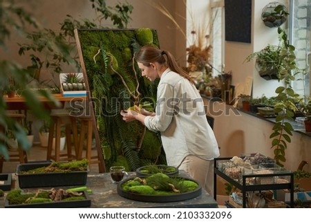 Young woman making picture with green plants