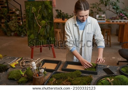 Pretty woman making picture with green plants