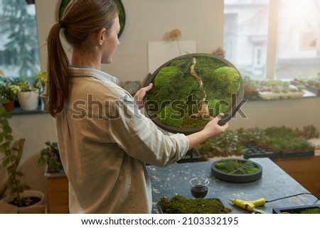 Young woman holding picture with green moss