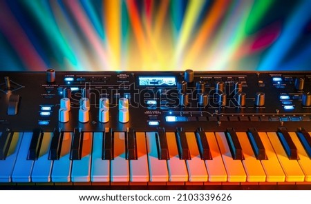 Musical instrument electronic synthesizer on a background of colored rays. Background on the theme of music, disco and synthesizer games. Royalty-Free Stock Photo #2103339626