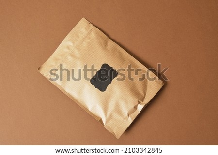 paper bag with black sticker for inscription on brown background Eco friendly packaging, paper recycling, zero waste, natural products concept. Copy space.