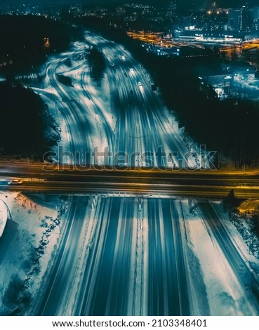 City street in winter night aerial view. The road is illuminated by lanterns. Drone view.