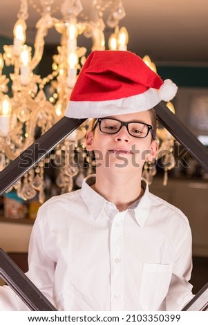 Boy with glasses and white shirt in front of festive candlestick and Christmas hat