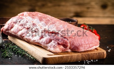 Raw pork on a cutting board with fresh tomatoes. On a wooden background. High quality photo
