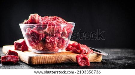 Raw sliced beef in a bowl on a cutting board. On a black background. High quality photo