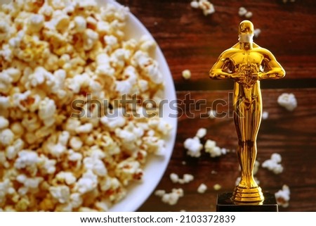 Hollywood Golden Oscar Academy award statue on popcorn background. Success and victory concept.