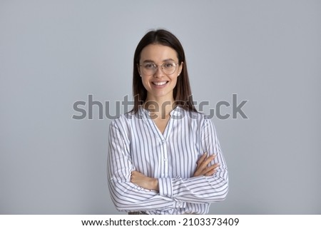 Happy millennial business woman in glasses posing with hands folded isolated on white, looking at camera, smiling. Confident female customer, young student girl, professional head shot portrait Royalty-Free Stock Photo #2103373409