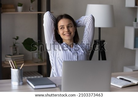 Happy relaxed millennial business woman resting at workplace, enjoying work break, looking away, thinking, smiling. Office employee breathing fresh air, feeling stress relief after completing task Royalty-Free Stock Photo #2103373463