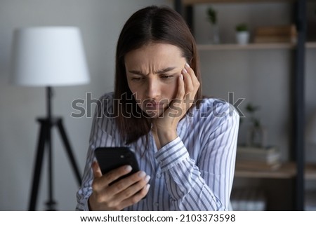 Frustrated annoyed smartphone user upset about problems with mobile phone, online app, virtual services, errors, mistakes, holding cellphone, looking at screen with frowning, angry, upset face Royalty-Free Stock Photo #2103373598