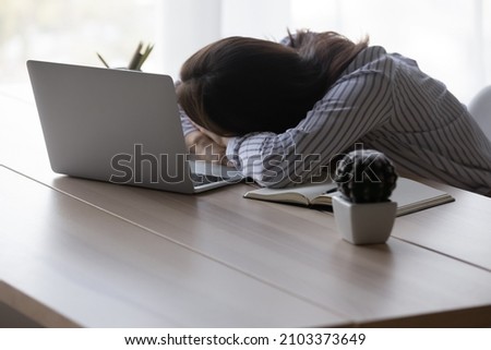 Exhausted tired office worker, employee woman sleeping at workplace, placing head on desk at laptop, feeling fatigue, burnout suffering from lack of energy, low productivity. Overwork concept Royalty-Free Stock Photo #2103373649