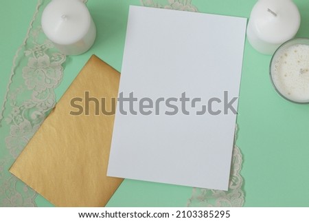 blank wedding invitation mockup with golden envelope, lace and candles on mint green background