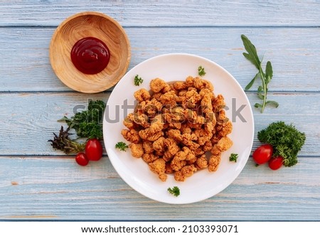 Homemade Crispy Popcorn Chicken in white plate with tomato ketchup and bbq sauce isolated on wooden table background top view fast food Royalty-Free Stock Photo #2103393071