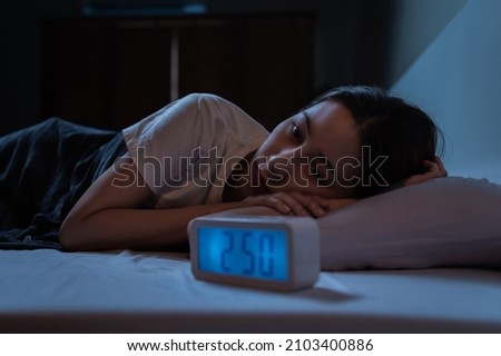 Young Asian woman suffer from insomnia can't sleep at night awaken from stress mental health problem or migraine. Young people health care psychiatry concept. Royalty-Free Stock Photo #2103400886