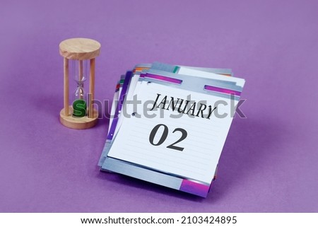 Calendar for January 2: loose-leaf calendar with the name of the month in English, numbers 02, hourglass on a pastel background