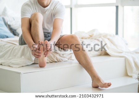 Foot pain, man suffering from feet ache at home, podiatry concept Royalty-Free Stock Photo #2103432971