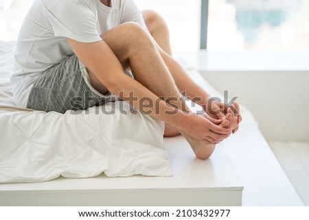 Foot pain, man suffering from feet ache at home, podiatry concept Royalty-Free Stock Photo #2103432977