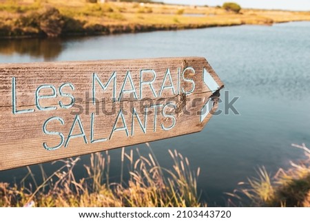 wooden sign indicating the direction of the salt marshes (Marais Salants) in front of a sea water sea