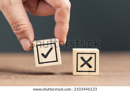 Closeup hand pick the right wood cube with correct sign, right and wrong choosing, make a decision concept